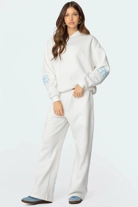 Détail du survêtement blanc pour femme avec motifs de nœuds bleus et tissu en tricot