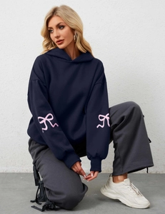 Detailed view of dark blue hoodie sleeve featuring large pink bow prints on the cuffs