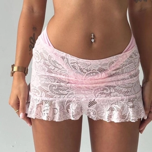Detail of light pink floral lace mini skirt with ruffled hem and intricate crochet texture