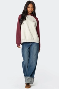 Dettaglio della felpa raglan con ricamo a fiocco rosso e coulisse sul cappuccio