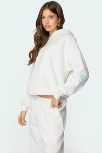 Détail de la manche d'un sweat à capuche blanc avec motif artistique bleu