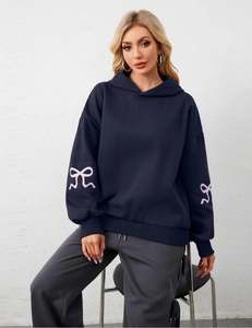 Detail view of navy blue hoodie featuring pink bow print on sleeve with casual fit