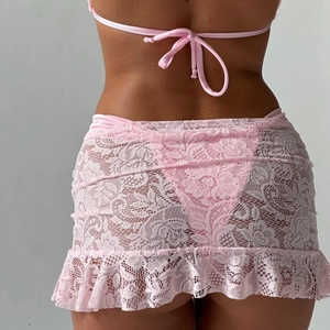 Close-up of pink lace beach cover-up with ruched floral design and ruffled hem detail