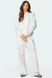 Détail de la manche d'un sweat blanc avec un imprimé graphique de nœud bleu clair