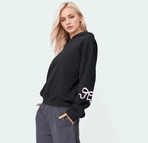 Detail of pink ribbon bow print on the sleeve of a black oversized hoodie