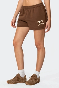 Dettaglio degli shorts in pile marrone con ricamo a fiocco bianco crema ed elastico
