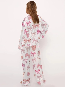 Women's pajama set featuring pink bow prints on white satin long sleeves and pants