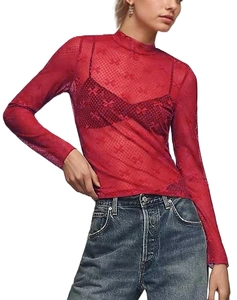 Detail view of red lace long sleeve top featuring mock neck and bow pattern mesh fabric