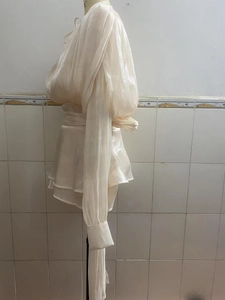 Detail view of champagne puff sleeve top with pleated fabric and ruffled hemline