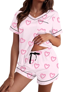 Detalle de pijama de satén rosa con estampado de corazones y ribetes en contraste