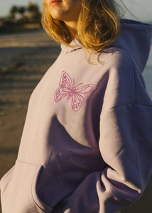 Detail of lavender oversized hoodie featuring a pink butterfly embroidery and front pocket