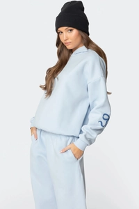 Vue détaillée du survêtement bleu clair avec imprimés papillons et profil latéral sur mannequin