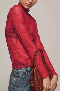 Detail of red sheer mesh top with delicate bow embroidery and mock neck design