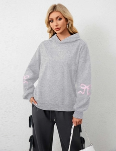 Detail of pink bow ribbon print on the sleeve of a grey oversized fleece hoodie