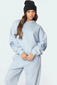 Détail du survêtement bleu clair avec motifs de rubans bleu foncé sur les manches du sweat à capuche