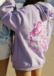 Detail of embroidered butterfly and inspirational slogan on a lavender oversized hoodie