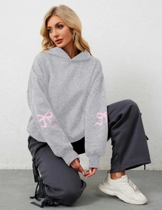 Detail showing the gray hoodie sleeve with a pink ribbon bow print and ribbed cuff
