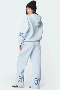 Détail du survêtement bleu clair avec imprimés nœuds bleu foncé sur les poignets et le pantalon