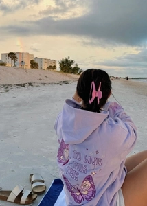Outdoor shot of lavender hoodie back featuring purple butterfly print and text detail