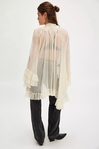 Detail view of layered ruffle cuffs and hem on a sheer beige chiffon blouse for women