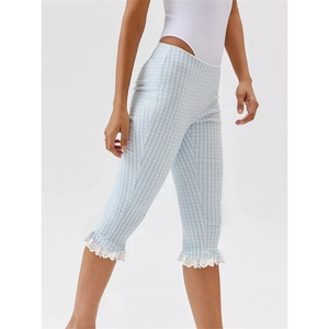 Detail of light blue gingham cropped trousers with delicate white lace trim on the hem