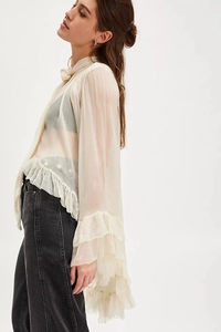 Detailed view of sheer cream chiffon top with ruffles and front neck tie detail
