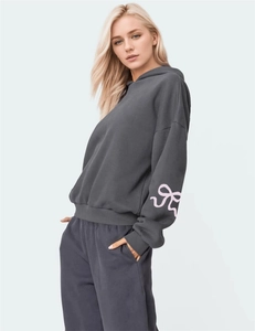 Detail of the pink ribbon bow print on the sleeve of a charcoal grey hooded sweatshirt