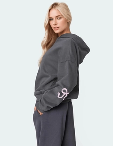 Detail view of oversized dark grey hoodie with pink sleeve graphics and ribbed cuffs