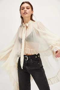Detail of sheer ivory chiffon top featuring tie-neck and flare ruffle cuffs
