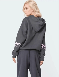 Detail of oversized dark grey hoodie with pink bow print on sleeves and dropped shoulders