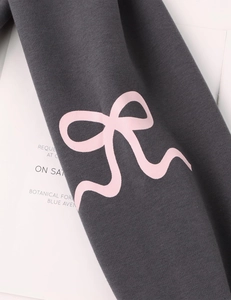 Macro view of pink ribbon bow print on dark grey knitted sweater fabric detail