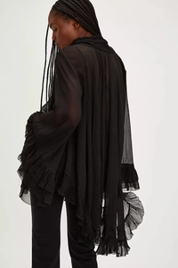 Detail of sheer black blouse featuring delicate layered ruffles and elegant flared sleeves