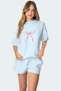 Détail d'un ensemble de détente bleu clair avec motifs de nœuds roses sur coton doux