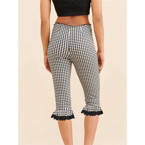 Close-up of black gingham capri leggings featuring ruffled hem and lace embroidery detail
