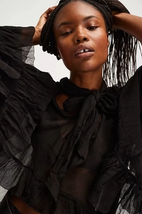Detailed view of black sheer mesh top with ruffles and adjustable neck tie design