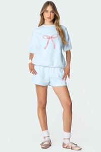 Détail d'un ensemble de détente bleu ciel avec imprimé nœud rose sur t-shirt et short