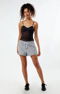 Detailed close-up of a black polka dot mesh tank top with a white bow and grey shorts