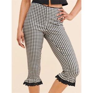 Detail view of black and white plaid capri pants with lace ruffle hem and slim fit cut