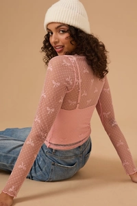 Detail of pink mesh long-sleeve top with bow patterns and lettuce-edge trim details