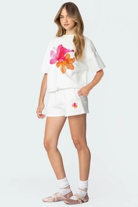 Détail des imprimés de lys sur le t-shirt en coton blanc et l'ensemble short assorti