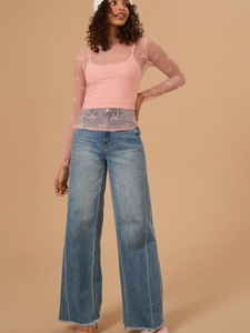 Pink sheer bow mesh top paired with wide-leg jeans and a white knit beanie hat