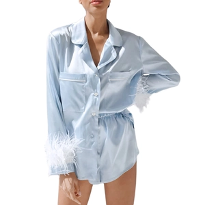 Detail of light blue satin pajama set featuring luxurious white feather cuffs and lapel