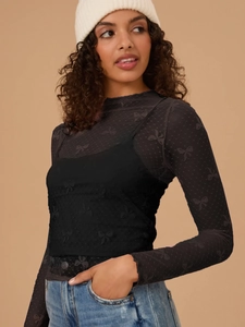 Close-up of black mesh long-sleeve top with elegant flocked bow patterns and inner camisole