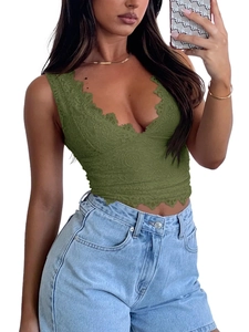Dettaglio del crop top in pizzo verde scuro con scollo a V, motivi floreali e bordi smerlati