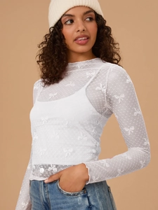 Detail of white mesh long sleeve top with bow jacquard patterns and polka dot textures