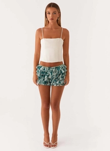 Detail of layered ruffle mini skirt in blue floral print paired with white strappy sandals