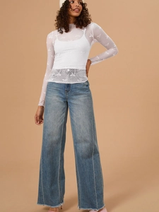Detail of white sheer mesh long sleeve tee with bow pattern and wide leg denim jeans