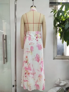 Detail of a backless halter floral maxi dress featuring elegant pink flowers on white fabric
