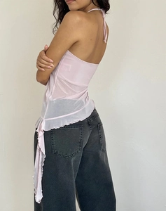 Détail du haut dos nu en tulle rose à volants et du jean en denim délavé gris