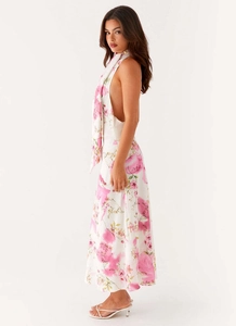 Detailed side view of backless halter dress with pink floral print and flowing fabric